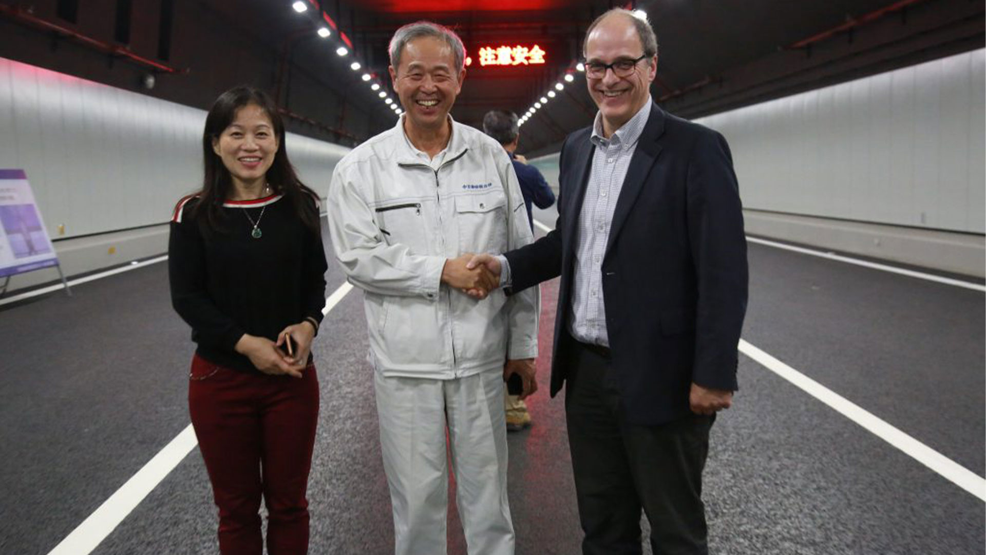 three people standing in a tunnel shaking hands