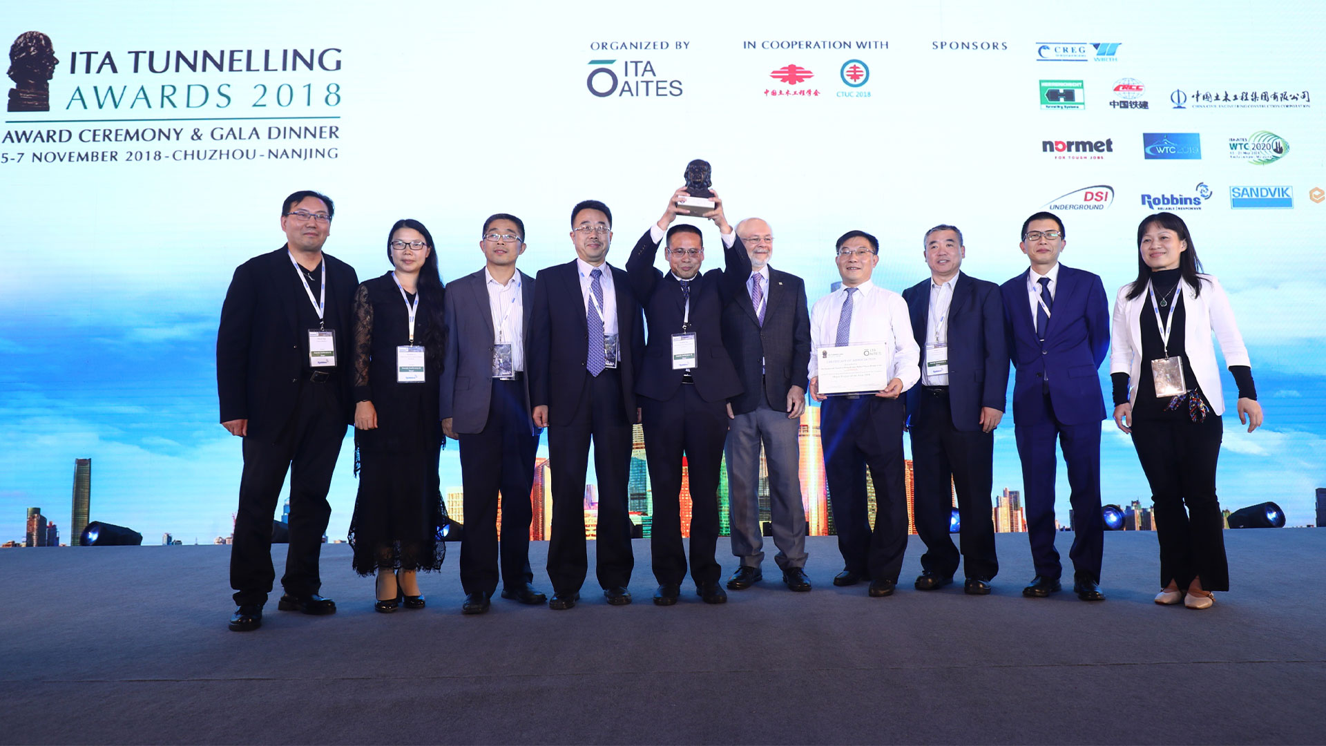 group of people posing in front of a banner at an event