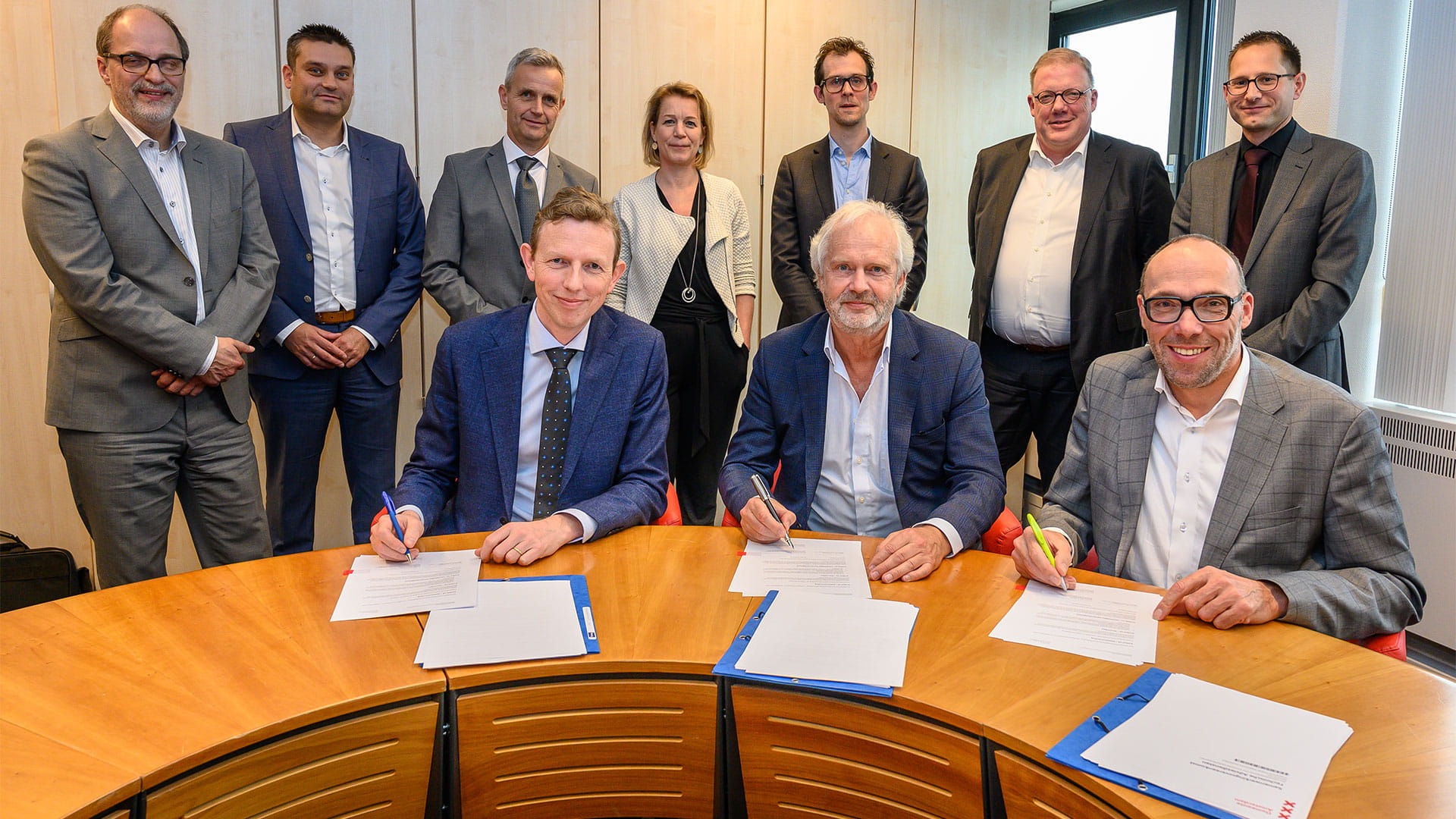 group of people sitting at a desk signing papers
